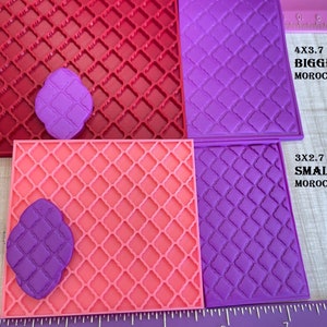 May include: Two silicone molds for making Moroccan tile designs. The larger mold is 4x3.7 inches and the smaller mold is 3x2.7 inches. Both molds are purple and have a diamond pattern.