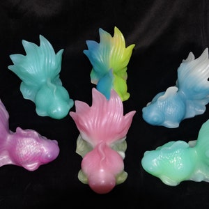 May include: Six colorful, hand-painted, ceramic goldfish figurines. Each figurine is in a different color, including pink, blue, green, and yellow.
