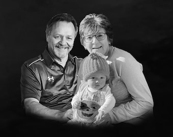 May include: A black and white photo of a family with a grandmother, grandfather, and a baby. The baby is wearing a knitted hat and a pumpkin-themed outfit. The grandparents are smiling and looking at the camera.