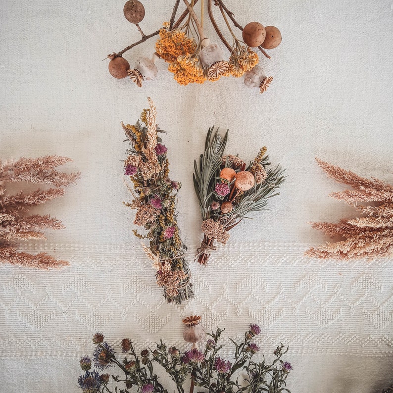 May include: Dried flower arrangements with a variety of dried flowers, including brown, beige, and pink flowers. The flowers are arranged in a bouquet and are tied together with twine.
