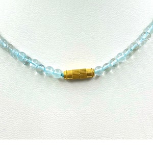 May include: A light blue gemstone necklace with a gold clasp.