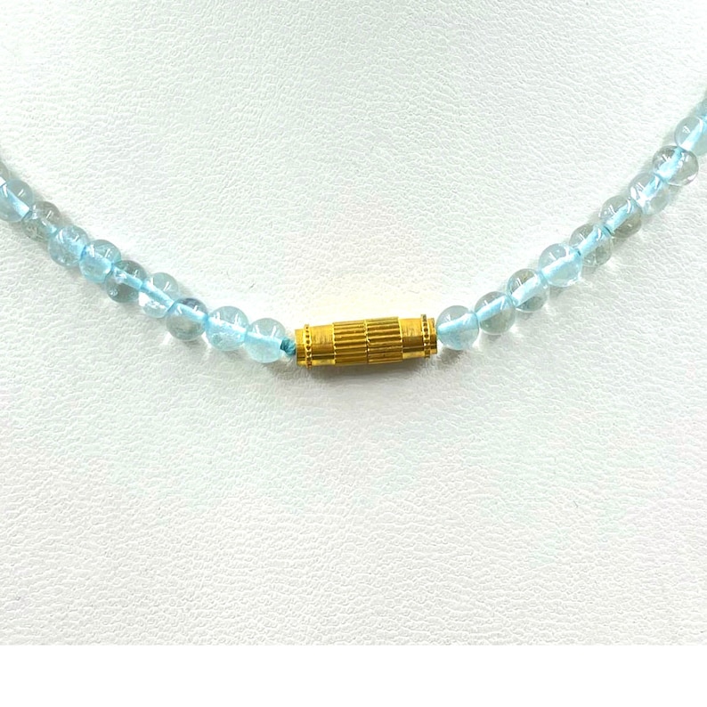 May include: A light blue gemstone necklace with a gold clasp.