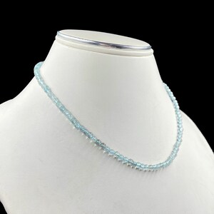 May include: A light blue gemstone necklace with round beads. The necklace is on a white mannequin bust.