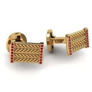 Puede incluir: Gemelos de oro con un diseño trenzado y detalles de piedras preciosas rojas.