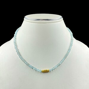 May include: A light blue gemstone necklace with a gold clasp. The necklace is made of small, round beads and is approximately 18 inches long.