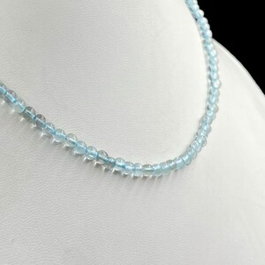May include: A delicate necklace made of light blue aquamarine beads. The necklace is strung on a clear thread and is approximately 18 inches long.