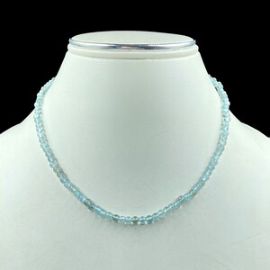 May include: A light blue gemstone necklace made of round beads. The necklace is on a white mannequin bust.