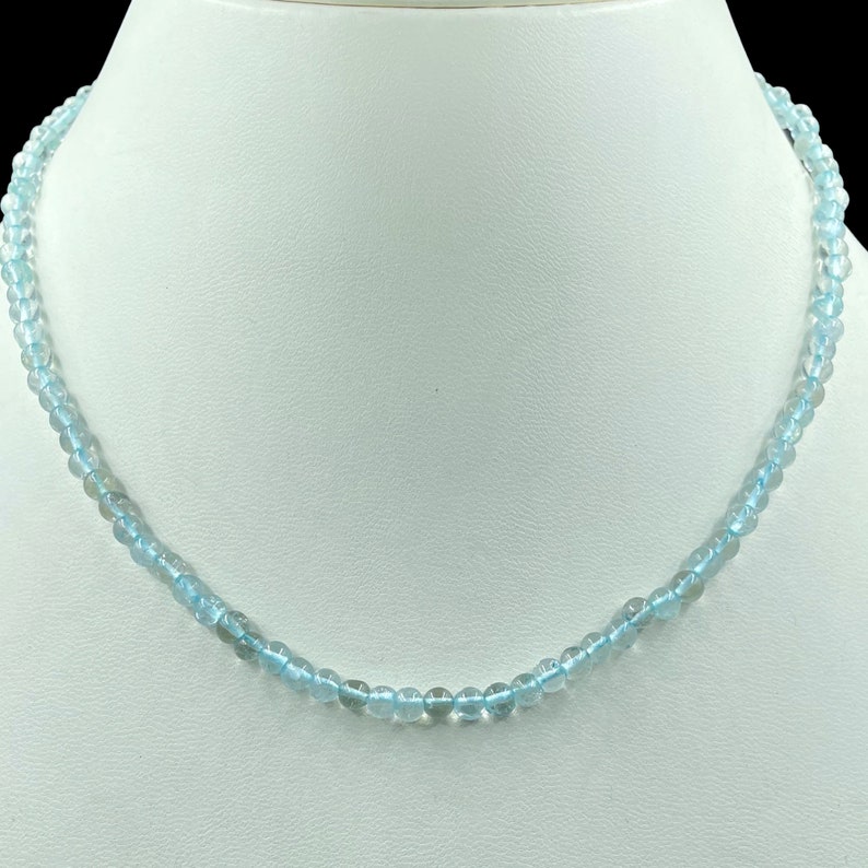 May include: A light blue aquamarine gemstone necklace with round beads.