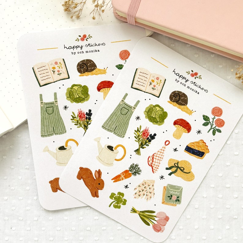 Pu&ograve; includere: Un foglio di adesivi a tema giardinaggio. Gli adesivi presentano illustrazioni di un annaffiatoio, una lumaca, un fungo, una torta, un libro, una salopette, un mazzo di fiori, una carota, un trifoglio, un paio di guanti da giardinaggio, una borsa da giardinaggio e un coniglio. Gli adesivi sono etichettati "happy stickers by ooh monika".