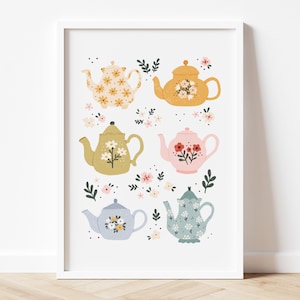 以下が含まれることがあります： 花柄のカラフルなティーポットが6つ描かれた白い額縁付きのプリント。各ティーポットは小さな花と葉で囲まれています。
