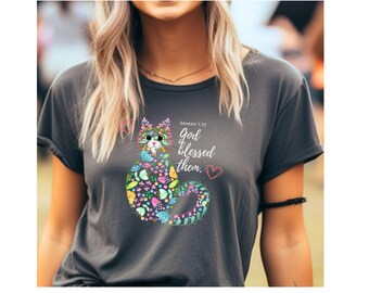May include: A dark gray t-shirt with a colorful cat illustration and the text "Genesis 1:22 God blessed them." The cat is made up of flowers and leaves.