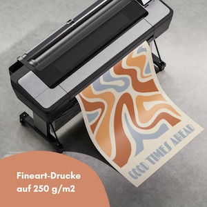 Puede incluir: Una impresora de gran formato imprime un p&oacute;ster con un dise&ntilde;o abstracto retro en tonos naranja, marr&oacute;n y azul. El p&oacute;ster dice "GOOD TIMES AHEAD". Tambi&eacute;n es visible el texto "Fineart-Drucke auf 250 g/m2".
