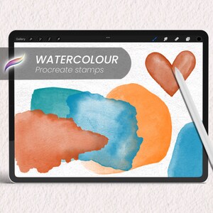 Op de afbeelding: Een digitaal tabletscherm waarop aquarel Procreate-stempels worden weergegeven. De stempels zijn in verschillende vormen en kleuren, waaronder oranje, blauw, groen en rood. De tekst "WATERCOLOUR Procreate stamps" wordt op het scherm weergegeven.