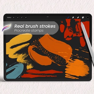 Peut inclure: Une tablette numérique affichant une collection de tampons de coups de pinceau colorés pour l'application Procreate. La tablette est noire avec une bordure blanche et est posée sur une surface blanche. Un stylet argenté est posé à côté de la tablette.