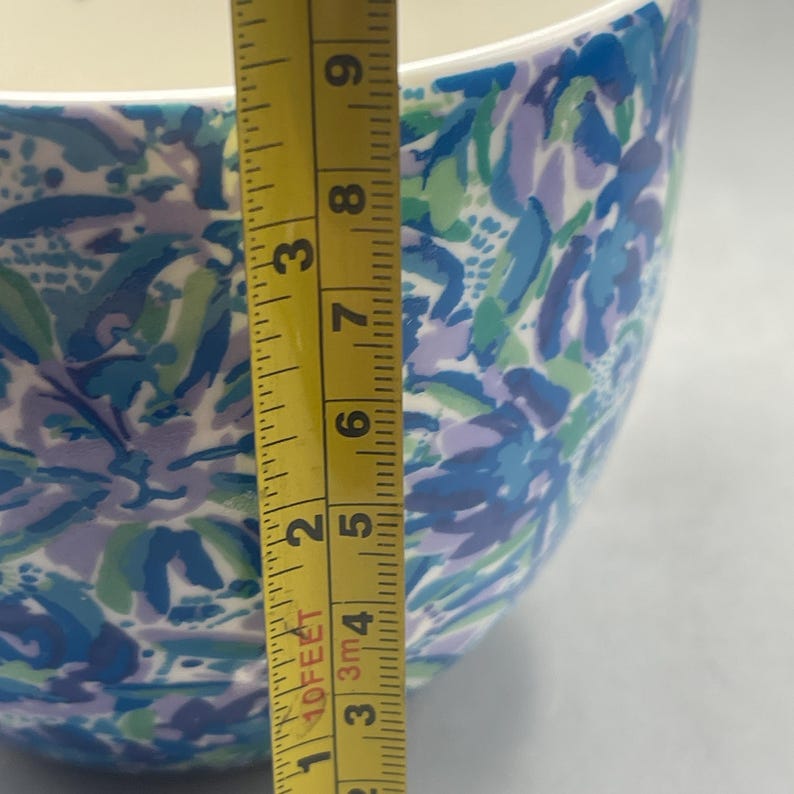 Puede incluir: Un cuenco de cer&aacute;mica con un estampado floral en tonos azules, verdes y morados. El cuenco mide aproximadamente 18 cm de alto. El interior es blanco. Una cinta m&eacute;trica amarilla est&aacute; al lado del cuenco.