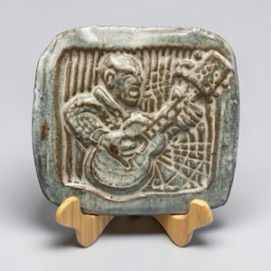 Op de afbeelding: Een set van drie keramische mokken met een gespikkelde, crèmekleurige glazuur. Elke mok heeft een ander handgeschilderd ontwerp: een blauw en groen blad, een gele zon en een roze bloem. De mokken hebben een eenvoudig, modern ontwerp.