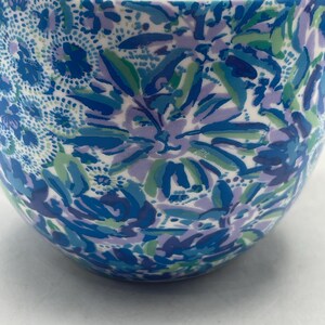 Puede incluir: Un cuenco de cer&aacute;mica con un estampado floral en tonos azules, verdes y morados. El dise&ntilde;o presenta flores y hojas estilizadas sobre un fondo blanco. La superficie del cuenco es lisa y brillante, con forma redondeada.