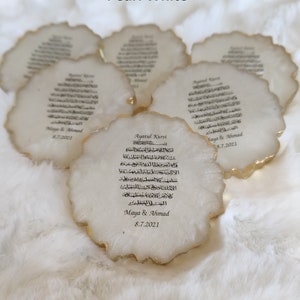 May include: White ceramic coaster with gold trim and Arabic calligraphy. The coaster features the text "Ayatul Kursi" and the names "Maya & Ahmad" with the date "8.7.2021".