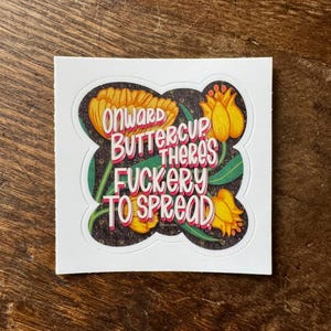 Puede incluir: Una pegatina blanca con un diseño floral negro. La pegatina presenta el texto "Onward Buttercup There's Fuckery To Spread" en una mezcla de fuentes rosas, blancas y naranjas. También se presentan tulipanes amarillos y naranjas.