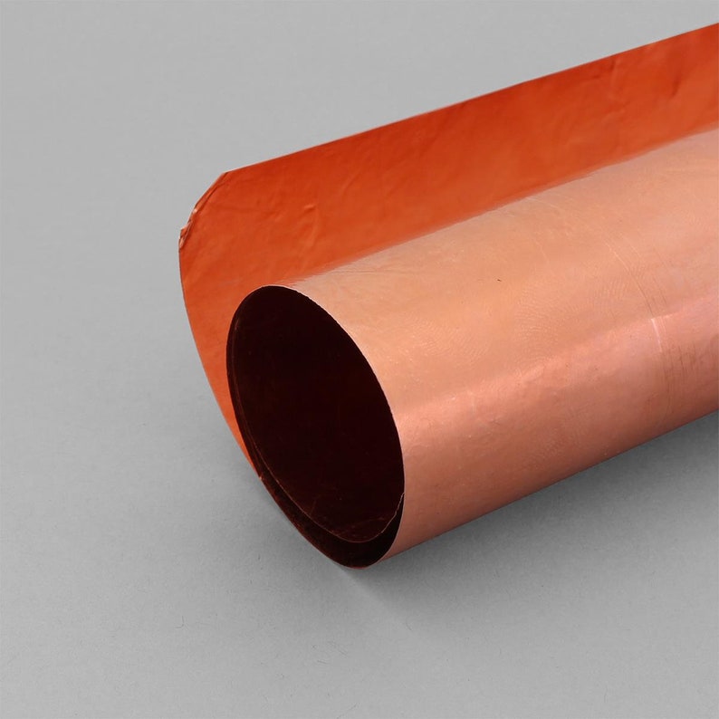 May include: A roll of copper foil with a shiny, metallic finish. The foil is rolled up and the edges are visible.