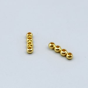 Peut inclure: Deux ensembles de perles en métal de couleur dorée, chaque ensemble composé de cinq perles enfilées en ligne.