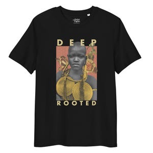 May include: Black t-shirt with a graphic featuring a portrait of a person with gold jewelry, set against a floral and dotted background. The words "DEEP ROOTED" are printed in a sans-serif font above and below the portrait.