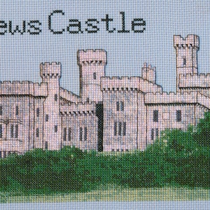 Puede incluir: Una imagen de punto de cruz de un castillo de piedra gris con múltiples torres, rodeado de árboles verdes. El texto "Lewis Castle" está en la parte superior de la imagen.