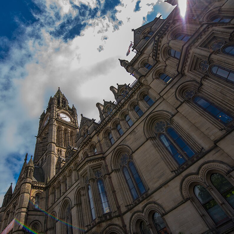 Puede incluir: Una vista de &aacute;ngulo bajo de un gran edificio ornamentado con una torre del reloj. El edificio est&aacute; hecho de piedra y tiene muchas ventanas. El cielo es azul y hay nubes en el cielo.