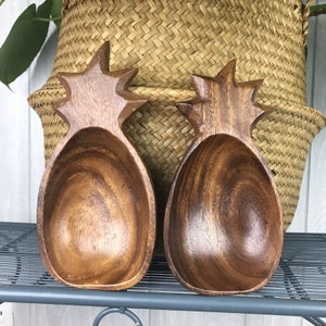 Pode incluir: Duas tigelas de madeira em forma de abacaxi. As tigelas são de cor castanho escuro e têm um acabamento liso e polido.