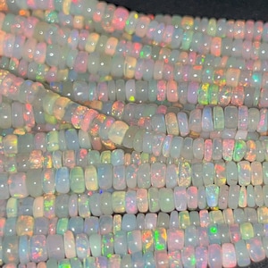 Peut inclure: Un brin de perles d'opale blanche avec des reflets arc-en-ciel irisés. Les perles sont petites et rondes, et elles sont enfilées sur un fil transparent.