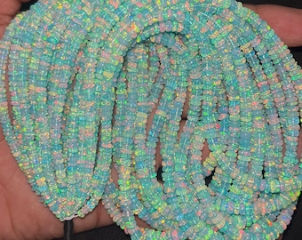 May include: A collection of iridescent opal beads, displaying a range of colors including blue, green, and pink. The beads are strung together, creating a necklace or bracelet. The opals have a polished, smooth surface, reflecting light and creating a shimmering effect.