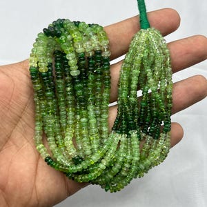 May include: A strand of green gemstone beads, ranging in colour from light to dark green. The beads are round and have a smooth, polished finish. The strand is approximately 18 inches long.