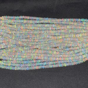 May include: A strand of white opal beads with iridescent rainbow flashes. The beads are small and round, and they are strung together on a clear thread.