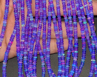Peut inclure: Plusieurs brins de perles d'opale violettes avec des éclats irisés. Les perles, petites et rondes, sont enfilées pour créer un collier ou un bracelet. Les opales présentent des nuances de bleu, de rose et de vert.