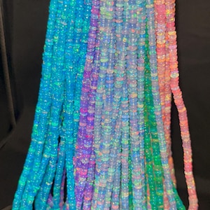 May include: Strands of colorful opal beads in shades of blue, purple, green, and pink. The beads are small and round, strung together to create a shimmering effect. The beads are likely used for jewelry making.