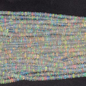 May include: A strand of iridescent white opal beads, each bead is a slightly different shape and size. The beads are strung on a clear thread and are ready to be used for jewellery making.