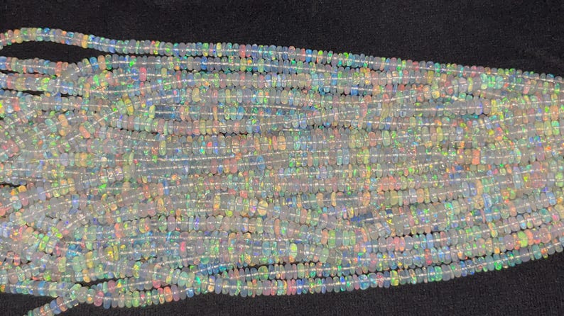 May include: A strand of iridescent white opal beads, each bead is a slightly different shape and size. The beads are strung on a clear thread and are ready to be used for jewellery making.
