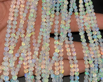 May include: A strand of white opal beads with iridescent rainbow flashes. The beads are round and smooth, and they are strung on a clear thread.