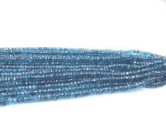 May include: A collection of small, faceted, blue-green beads. The beads are strung together, creating a layered effect. The beads are a deep teal colour, and the image is set against a white background.