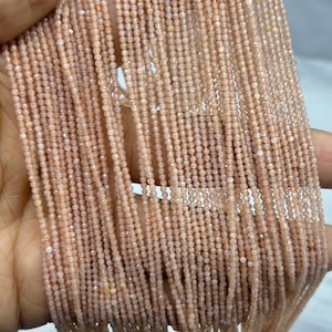 May include: Close-up of multiple strands of small, peach-toned gemstone beads. The beads are evenly sized and shaped, creating a flowing, textured effect. Perfect for jewellery making, these beads have a soft, warm colour.