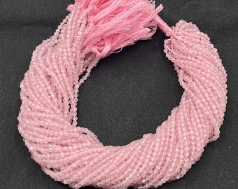 May include: A strand of pink rose quartz beads, approximately 4mm in size, with a tassel at the end. The beads are faceted and have a translucent appearance.