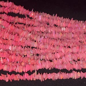 May include: A strand of pink opal chip beads. The beads are irregular in shape and have a natural, rough texture.