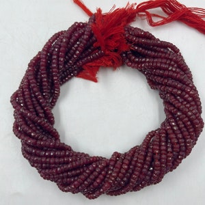 May include: A strand of deep red faceted gemstone beads. The beads are small and uniform in size, and the strand is long enough to make a necklace or bracelet.