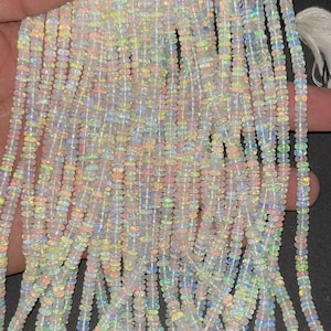 May include: A strand of white opal beads with iridescent rainbow flashes. The beads are small and round, and they are strung on a clear thread. The strand is approximately 18 inches long.