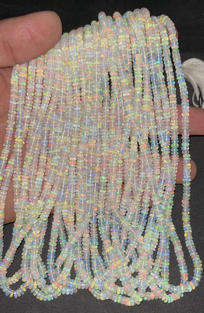 May include: A strand of white opal beads with iridescent rainbow flashes. The beads are small and round, and they are strung on a clear thread. The strand is approximately 18 inches long.