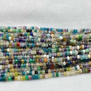 Può includere: Un filo di perline di pietre preziose multicolori, tra cui blu, verde, giallo e viola, con una varietà di forme e dimensioni.