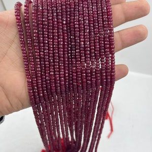 May include: A strand of deep red ruby beads, faceted and strung on a thin thread. The beads are small and uniform in size, creating a continuous line of colour.