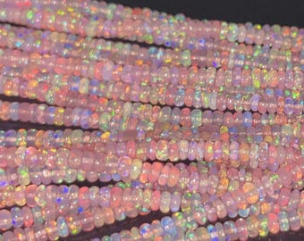 May include: Close-up of multiple strands of pink opal beads. The beads are small, round, and have a subtle iridescent sheen, with flashes of color. The beads are strung together, creating a textured and visually appealing display. Ideal for jewelry making.