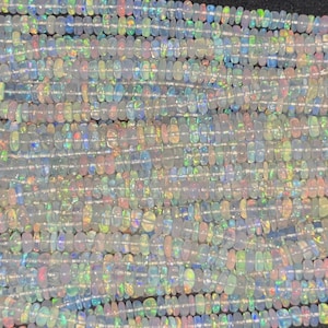 May include: A strand of white opal beads with iridescent rainbow flashes. The beads are small and round, and they are strung on a clear thread.