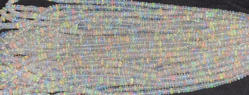 May include: A strand of white opal beads with iridescent rainbow flashes. The beads are small and round, and they are strung on a clear thread.
